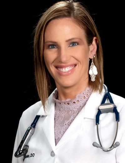 Smiling doctor in a white coat with a stethoscope against a black background