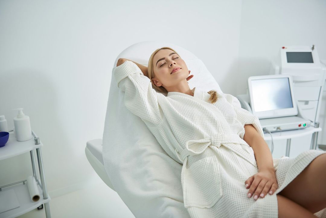 Arm in a white wrist brace with red light shining on the wrist while resting on a chair