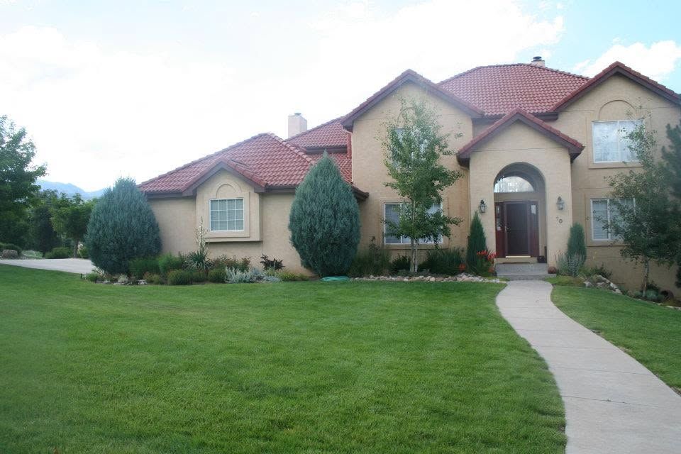 Cream-colored suburban house with red roof, arched entry, and a curved walkway across a green lawn
