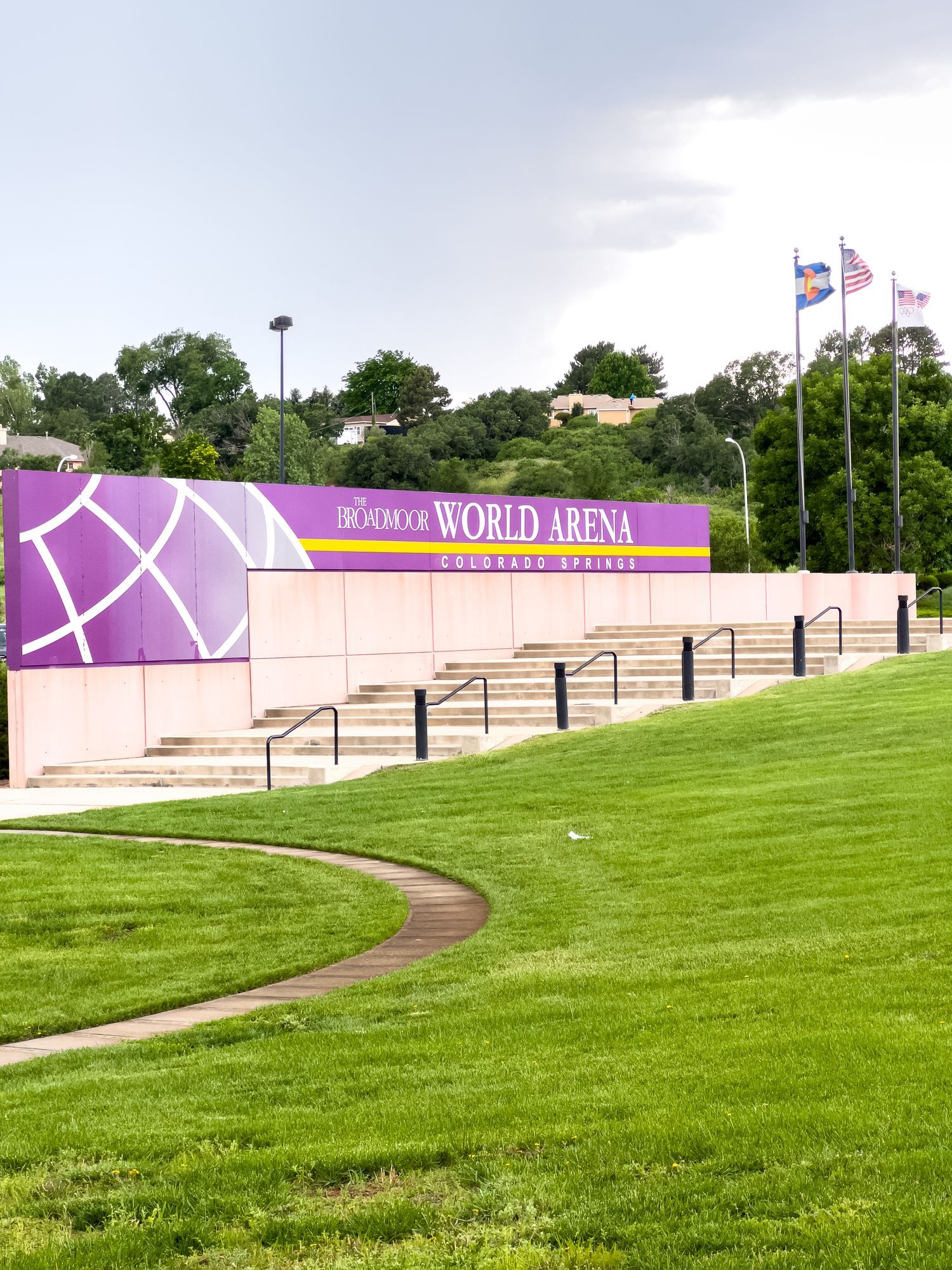 World Dream sign beside a grassy hill and flagpoles under a cloudy sky