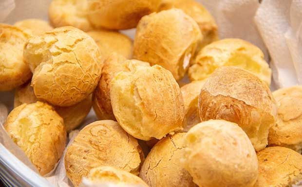 Pãezinhos de queijo dourados e assados ​​em uma cesta.
