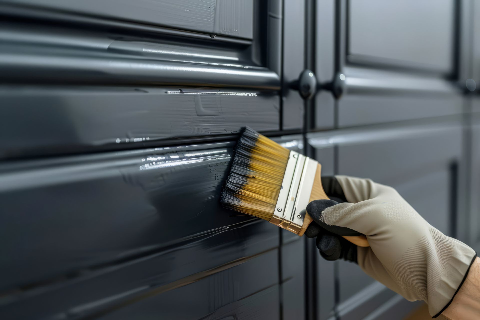 A person is painting a black cabinet with a brush.