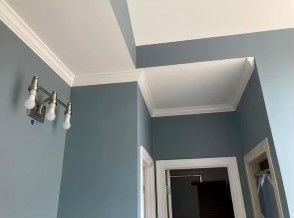 A bathroom with blue walls and white trim and a light fixture on the wall.