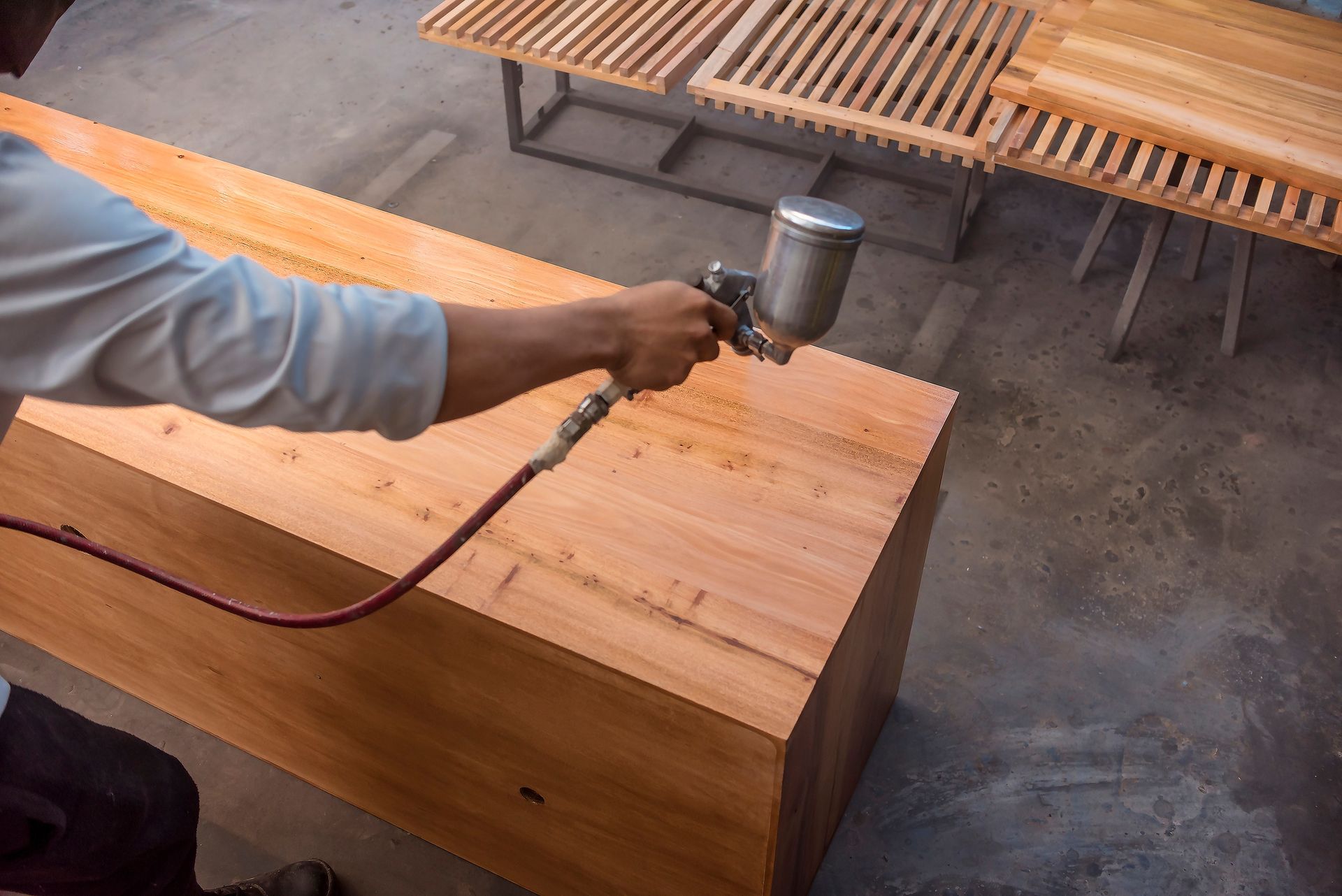 A man is spraying paint on a piece of wood.