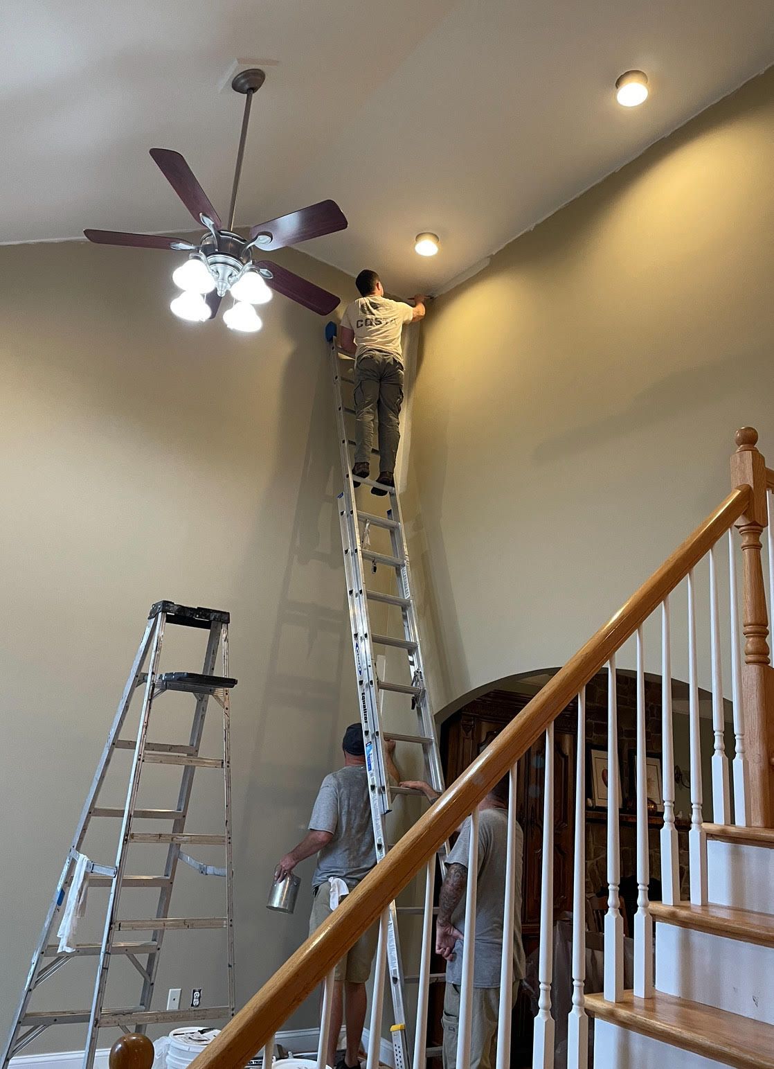 A group of people are painting a wall in a house.