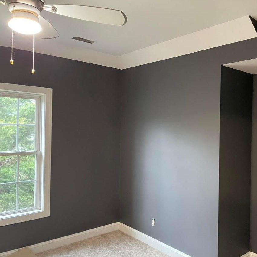 An empty room with a ceiling fan and a window.