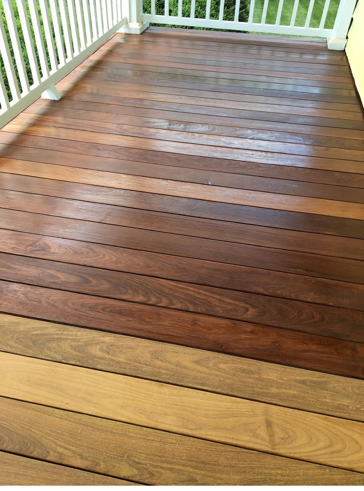 A close up of a wooden deck with a white railing.