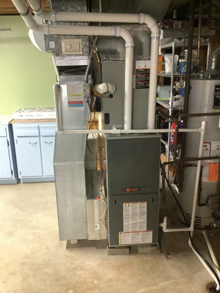Furnace, air handler, and water heater in a basement. Ductwork and piping are visible.