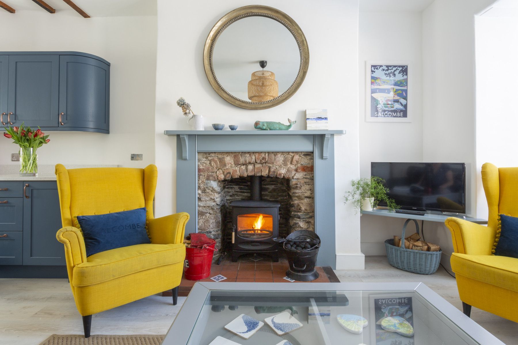 Cozy living room with yellow armchairs, fireplace, and blue cabinets.