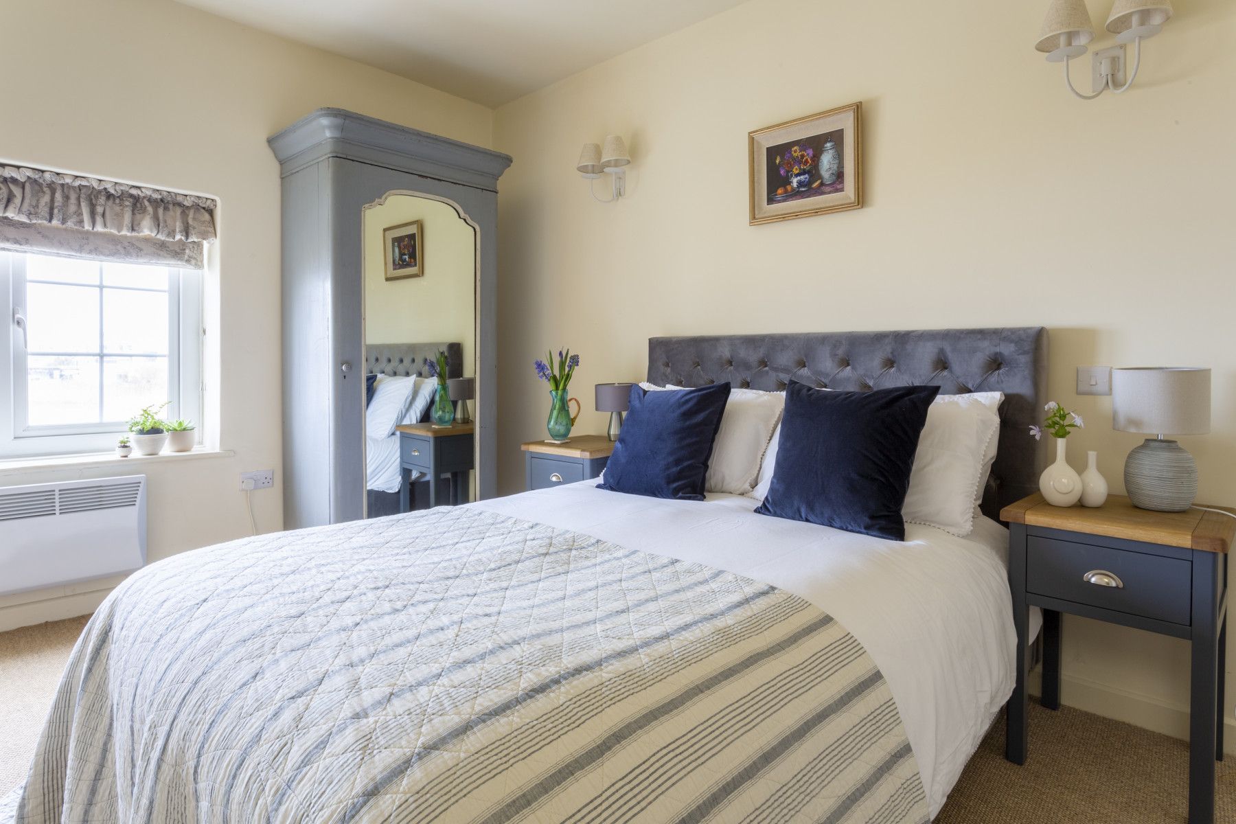Bedroom with bed, tall gray wardrobe, nightstand, and window.