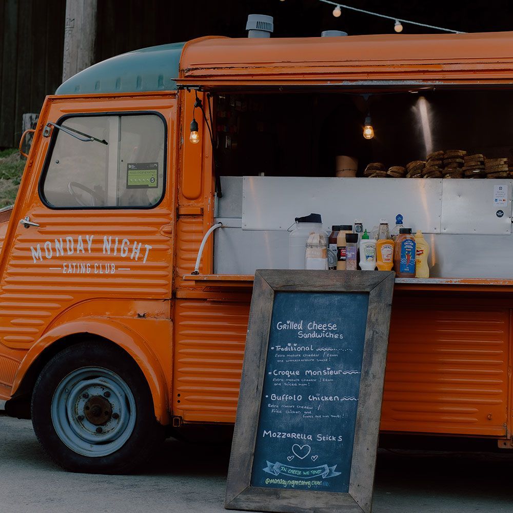 Orange food truck with an open service window and a chalkboard menu.