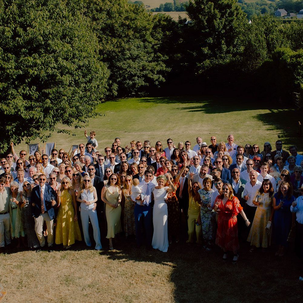Large group of people gathered outdoors, possibly at a wedding. They are smiling and looking at the camera.