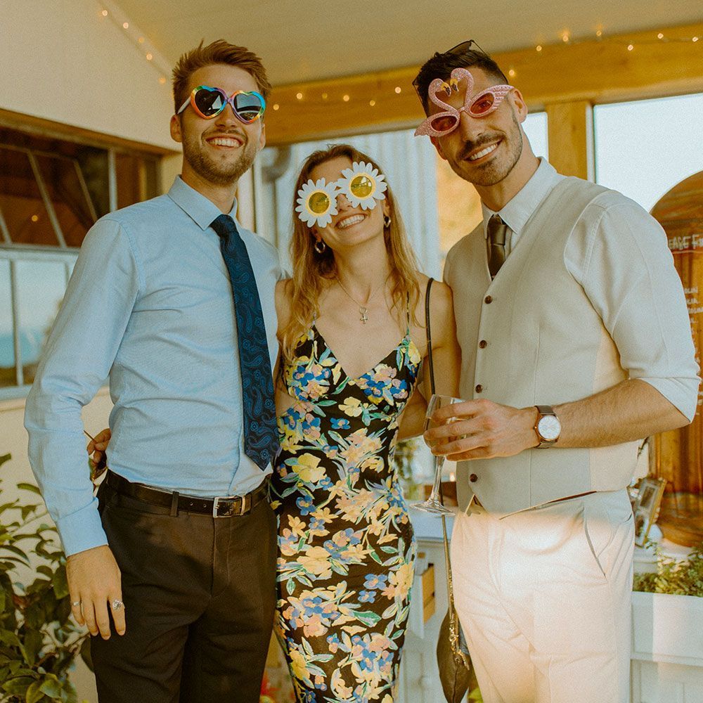 Three people wearing novelty sunglasses at an outdoor event.