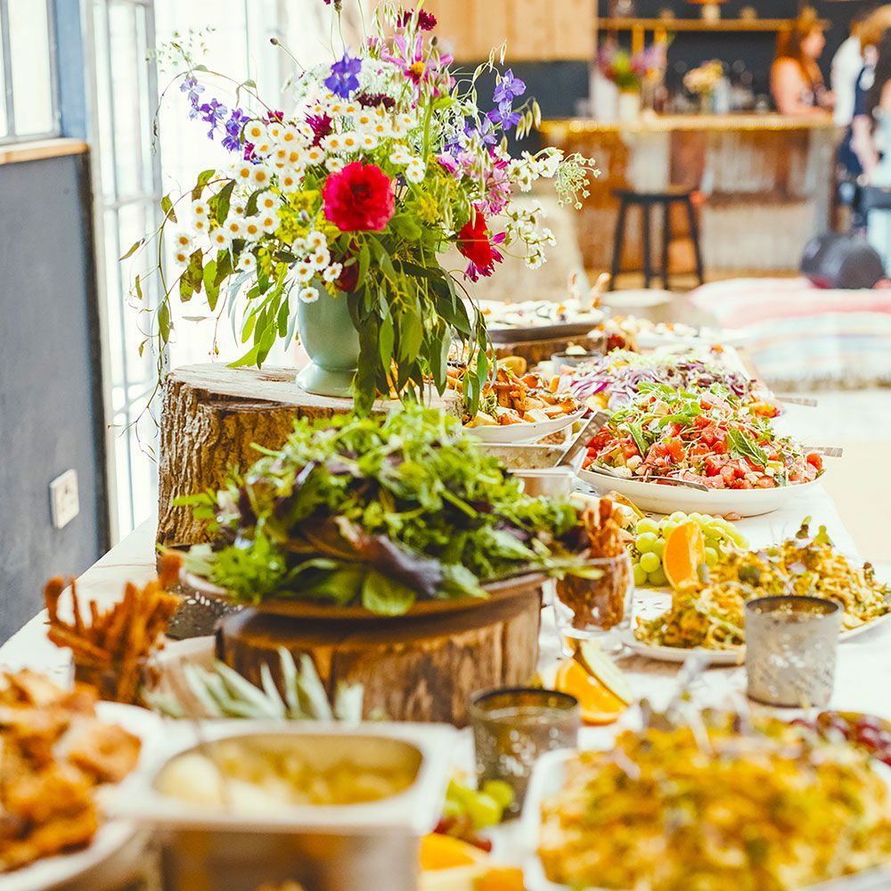 Buffet table with various salads and flowers.