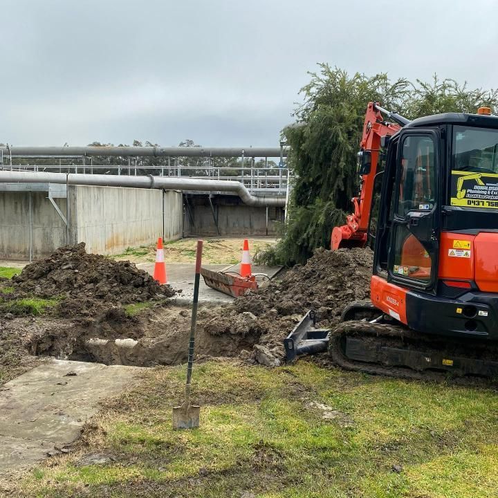 Bulldozer is Digging a Hole in the Ground in a Field — Donaldson Plumbing & Excavations in Baranduda, VIC