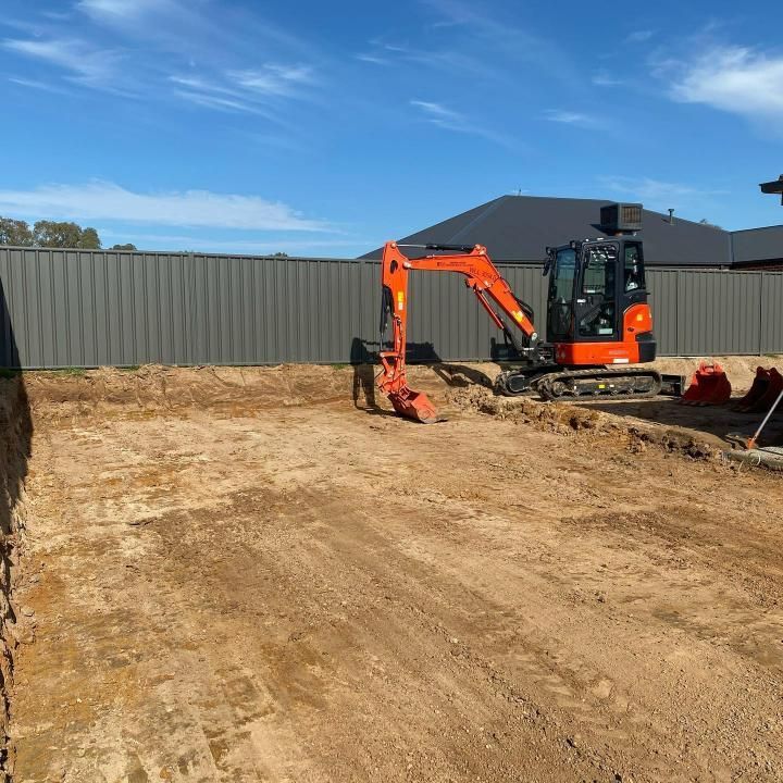 Orange Excavator is Digging a Hole in a Dirt Field — Donaldson Plumbing & Excavations in Wodonga, VIC
