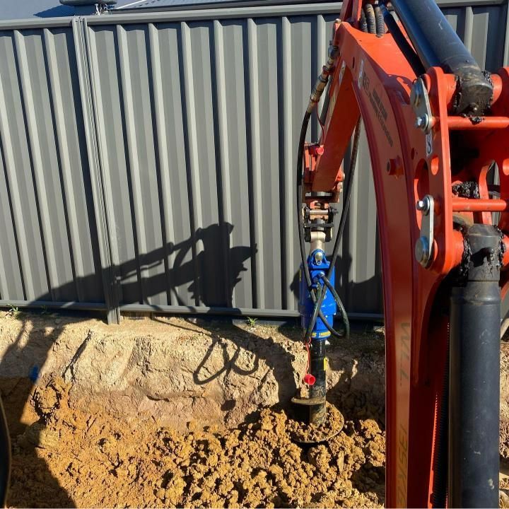 Orange Excavator Drilling a Hole in Brown Soil — Donaldson Plumbing & Excavations in Albury, NSW