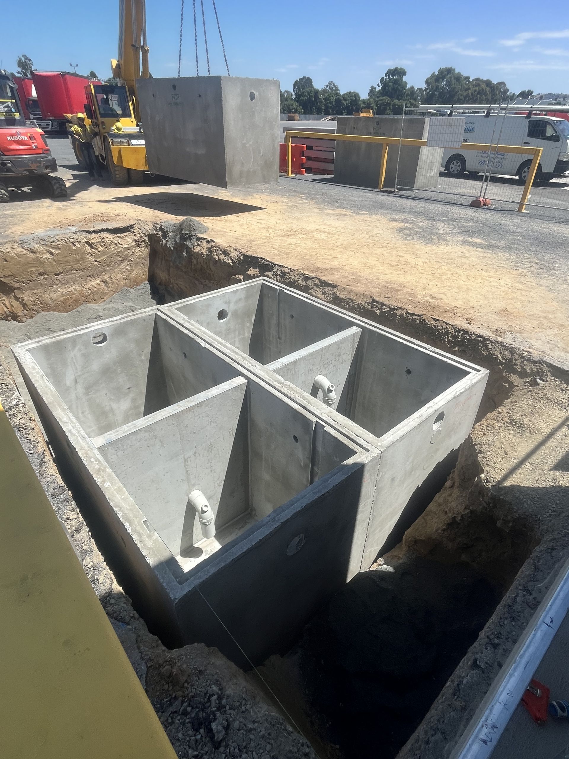 Concrete Tank Being Lowered Into a Pit by a Crane — Donaldson Plumbing & Excavations in Baranduda, VIC
