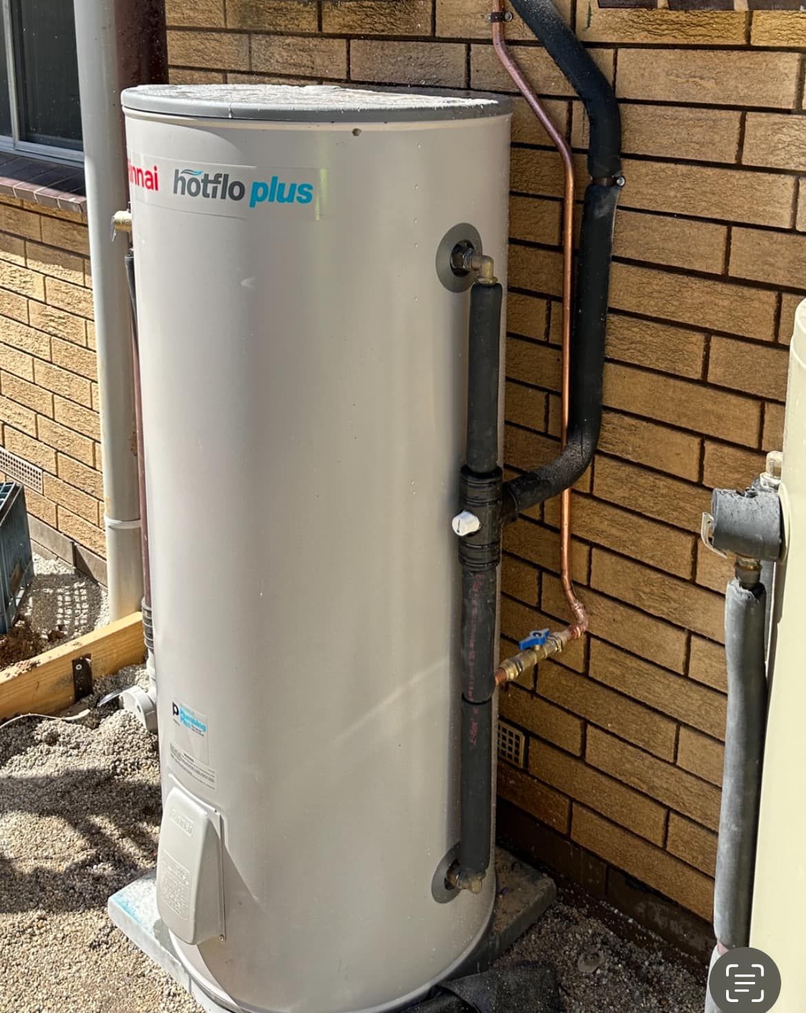White Water Heater is Sitting on the Side of a Brick Building — Donaldson Plumbing & Excavations in Chiltern, VIC