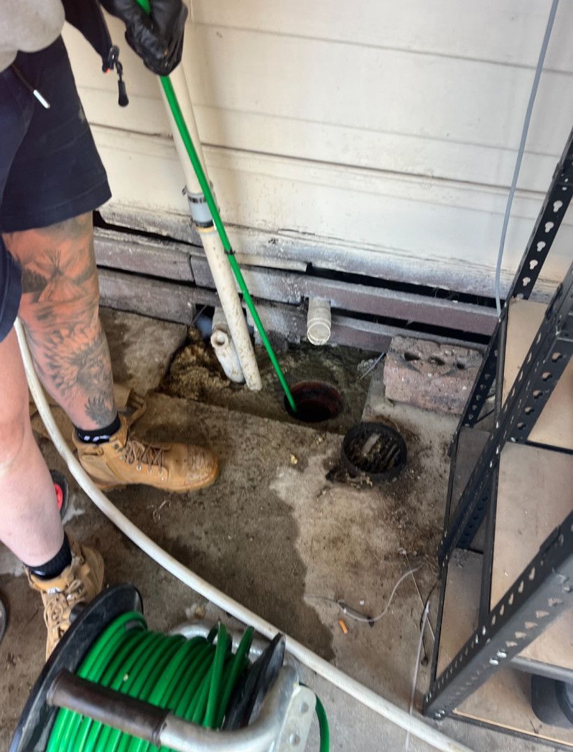 A Plumber Uses a Stick to Unclog a Drain — Donaldson Plumbing & Excavations in Baranduda, VIC