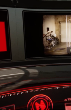 Car dashboard screen showing a small video of a person on a bicycle indoors.