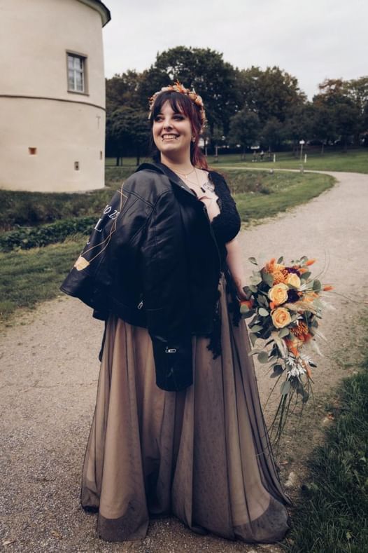 Eine Frau in einem langen Kleid hält einen Blumenstrauß.
