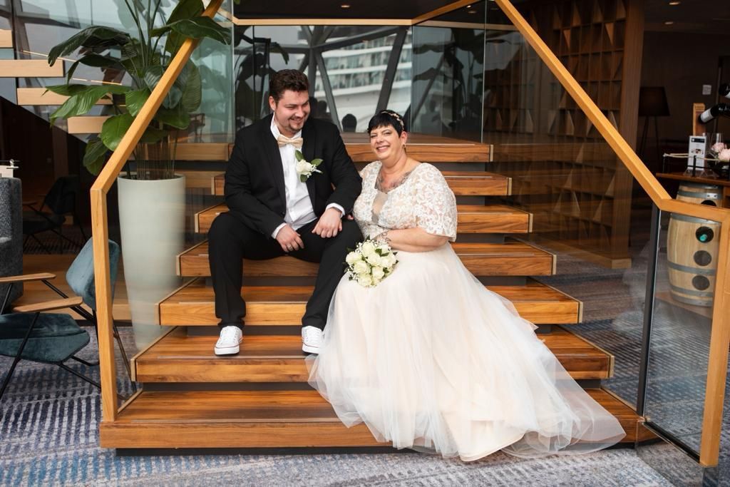 Eine Braut und ein Bräutigam sitzen auf der Treppe eines Gebäudes.