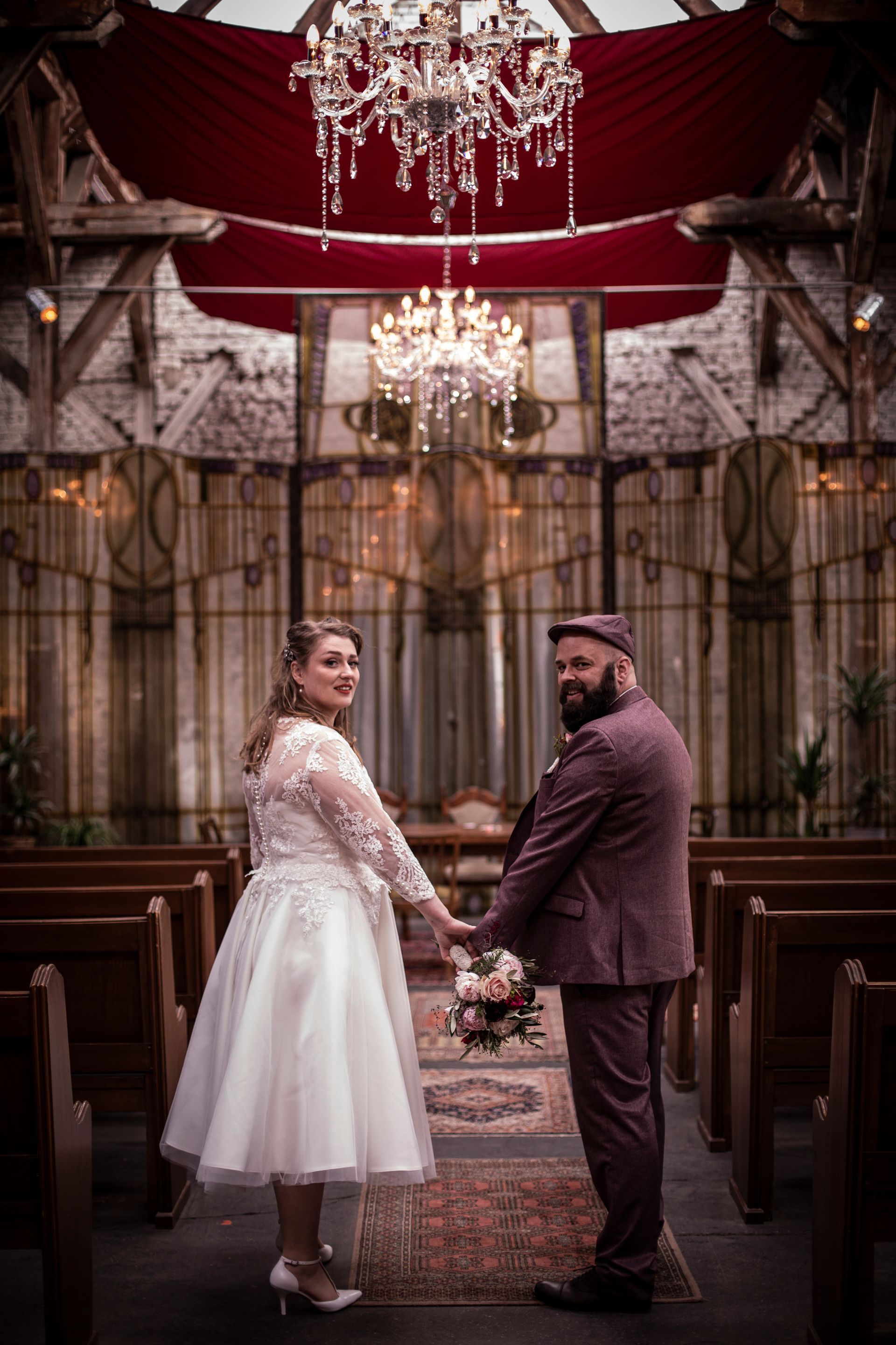 Eine Braut und ein Bräutigam halten in einer Kirche Händchen.