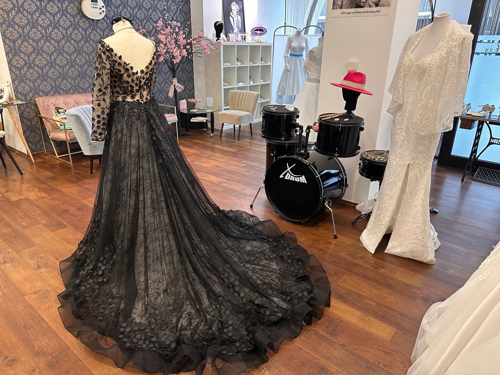 In einem Geschäft ist neben einem Schlagzeug ein schwarzes Kleid ausgestellt.