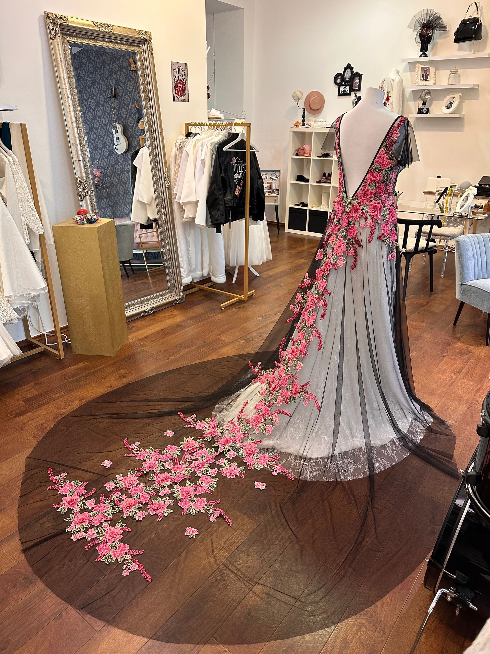 Ein Kleid mit rosa Blumen liegt auf einem Holzboden in einem Zimmer.