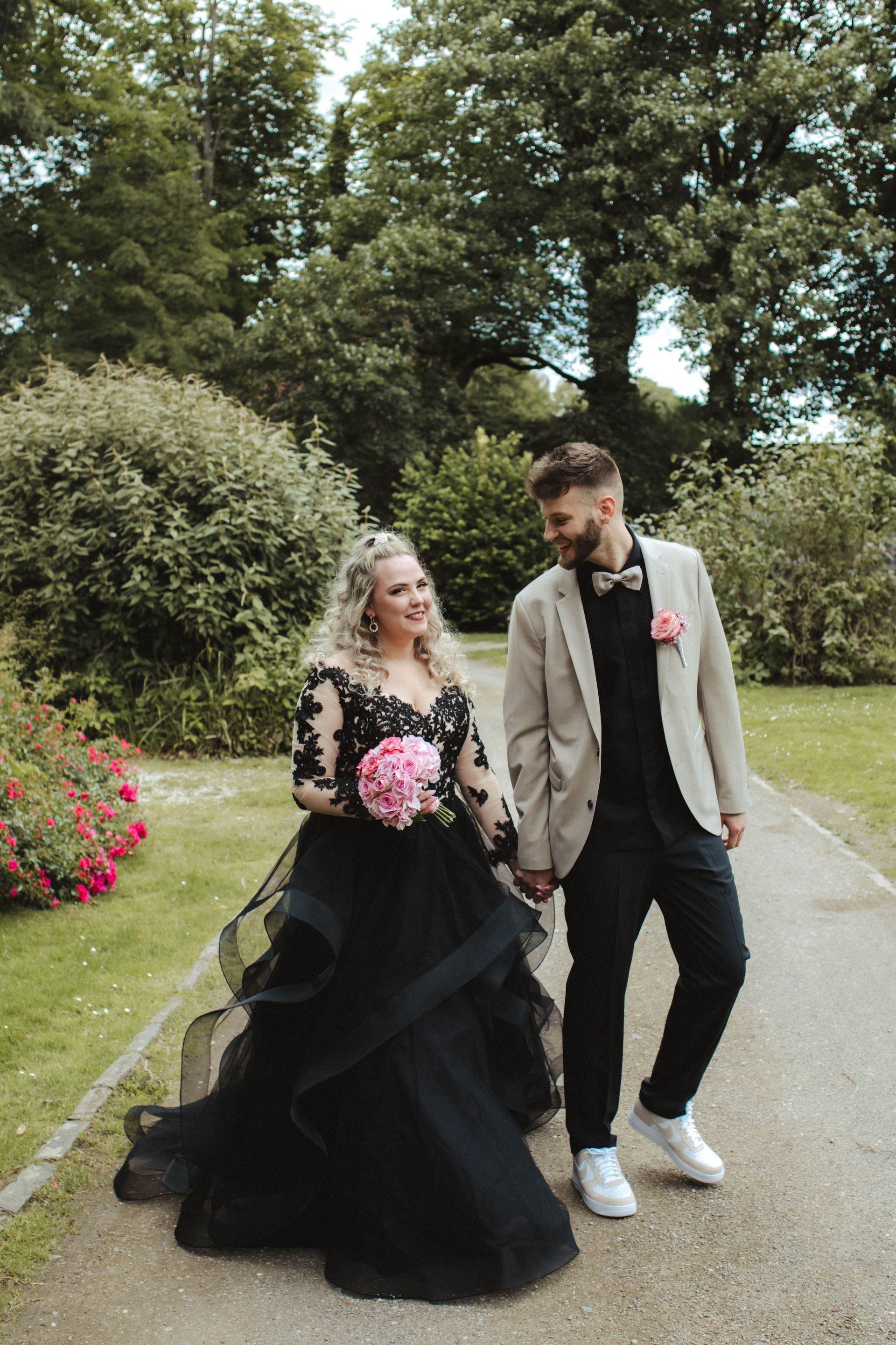 Die Braut trägt ein schwarzes Kleid und der Bräutigam eine hellbraune Jacke.