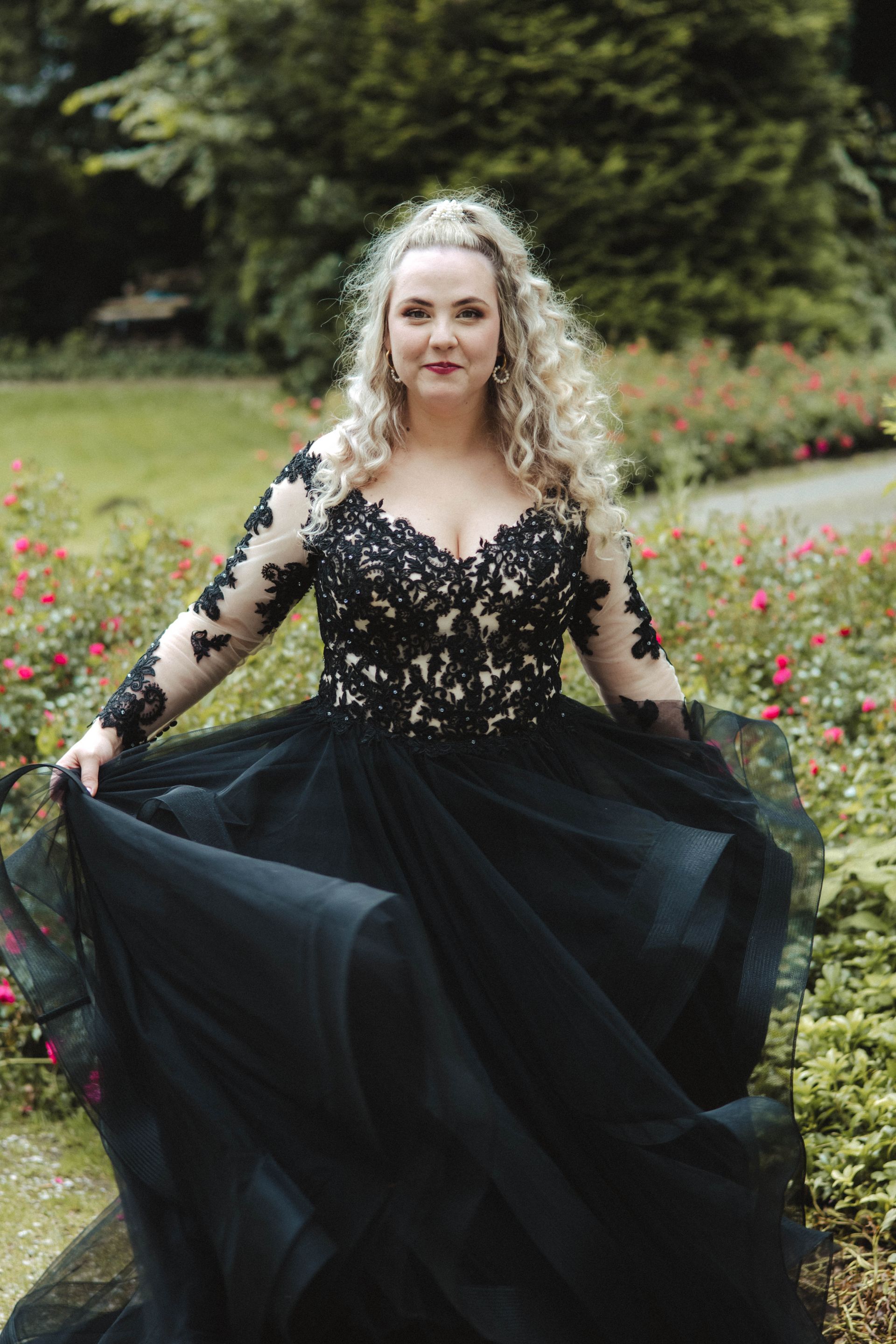 Eine Frau in einem schwarzen Kleid steht in einem Blumenfeld.