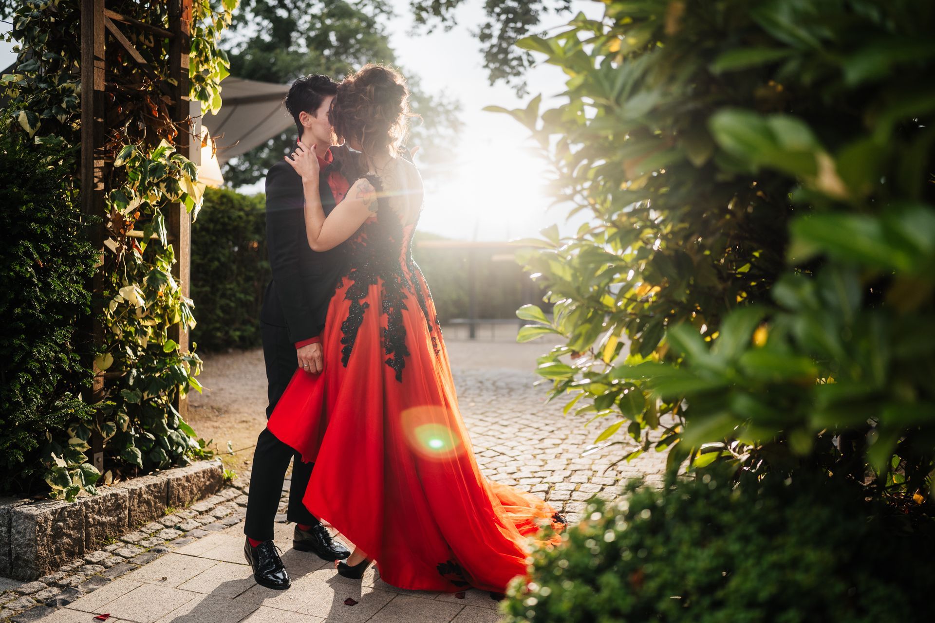 Ein Mann in einem schwarzen Anzug und eine Frau in einem roten Kleid küssen sich.