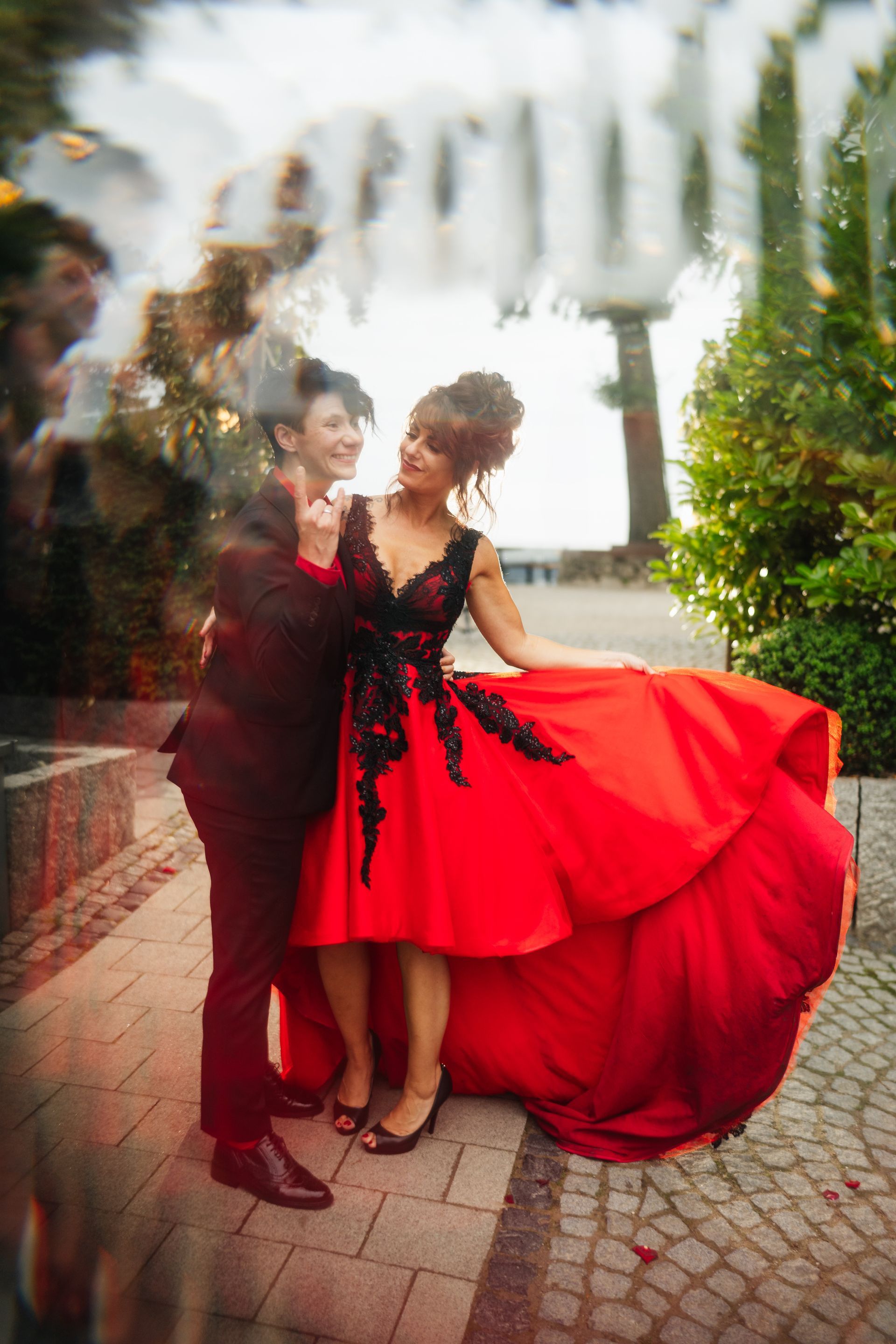Ein Mann im Anzug und eine Frau im roten Kleid stehen nebeneinander auf einem Bürgersteig.
