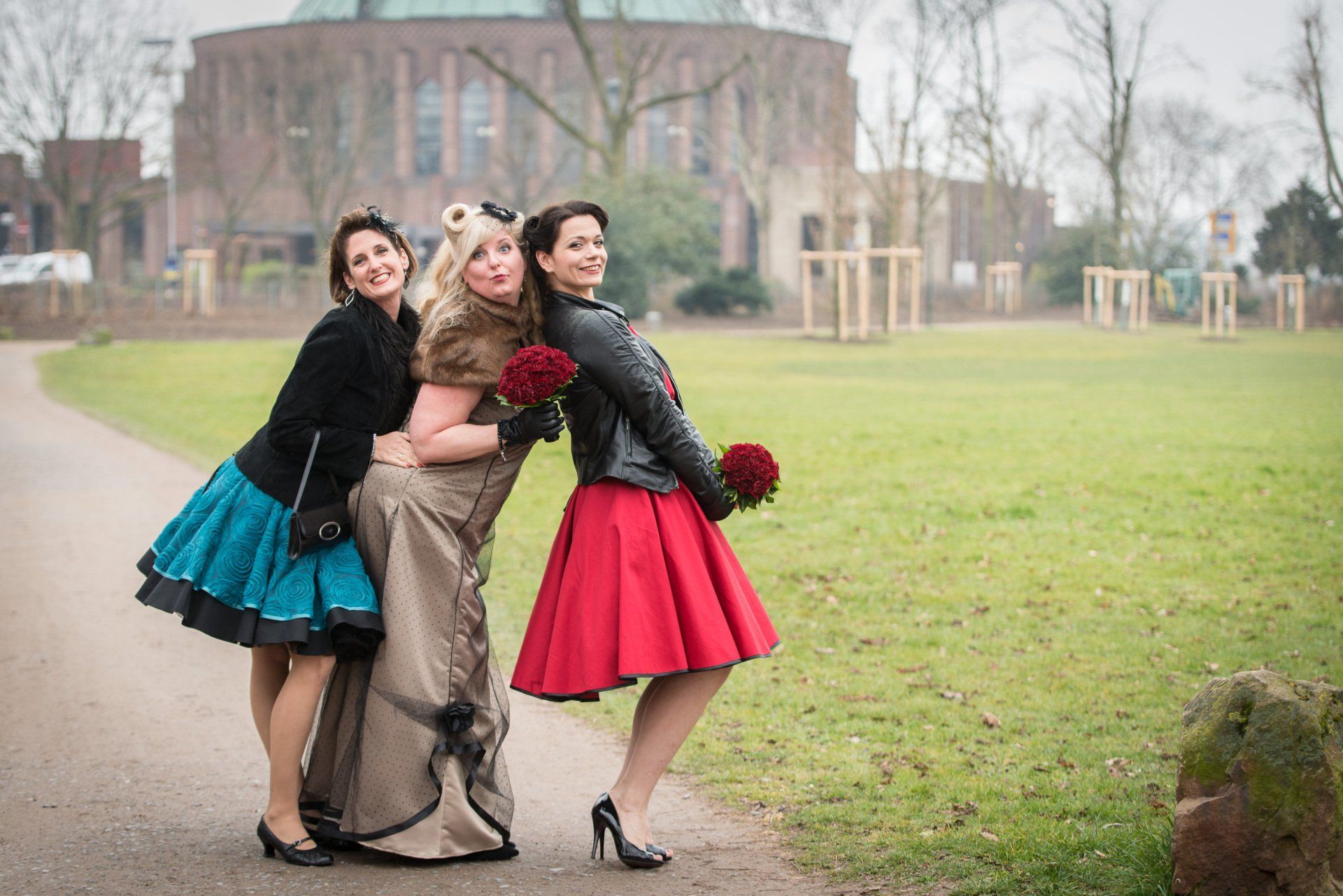 Drei Frauen posieren in einem Park für ein Foto.