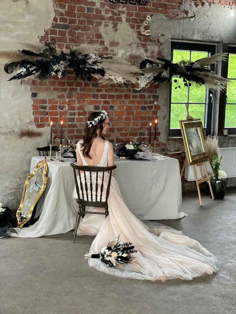 Eine Braut im Brautkleid sitzt an einem Tisch.