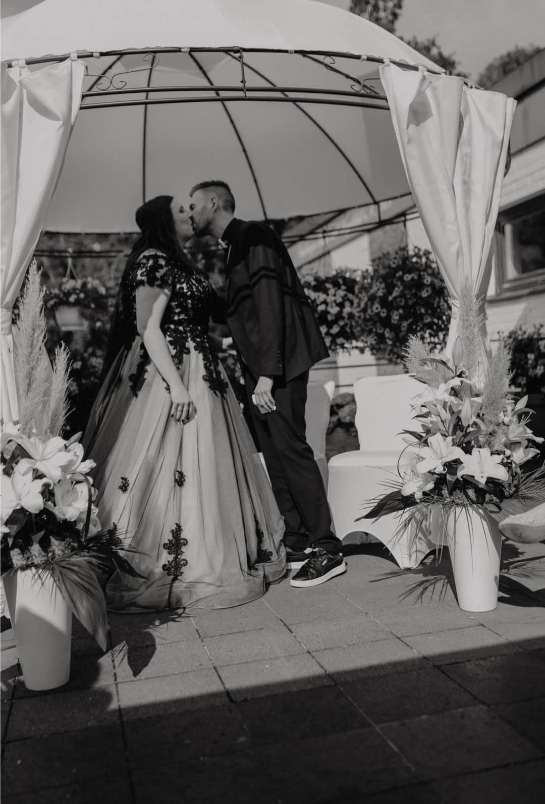 Eine Braut und ein Bräutigam küssen sich bei ihrer Hochzeit unter einem Pavillon.