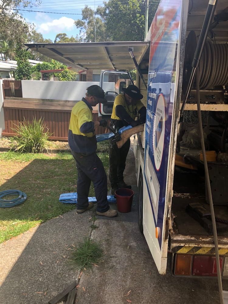 Two Men Are Working on a Truck in a Yard — FlowWise in Maroochydore, QLD