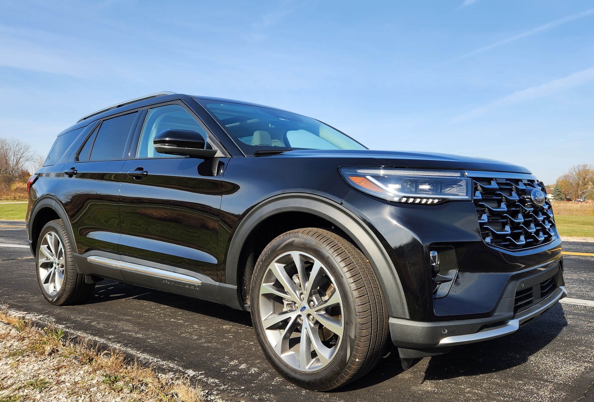 Black SUV parked on a roadside under a blue sky, viewed from the front-left side.