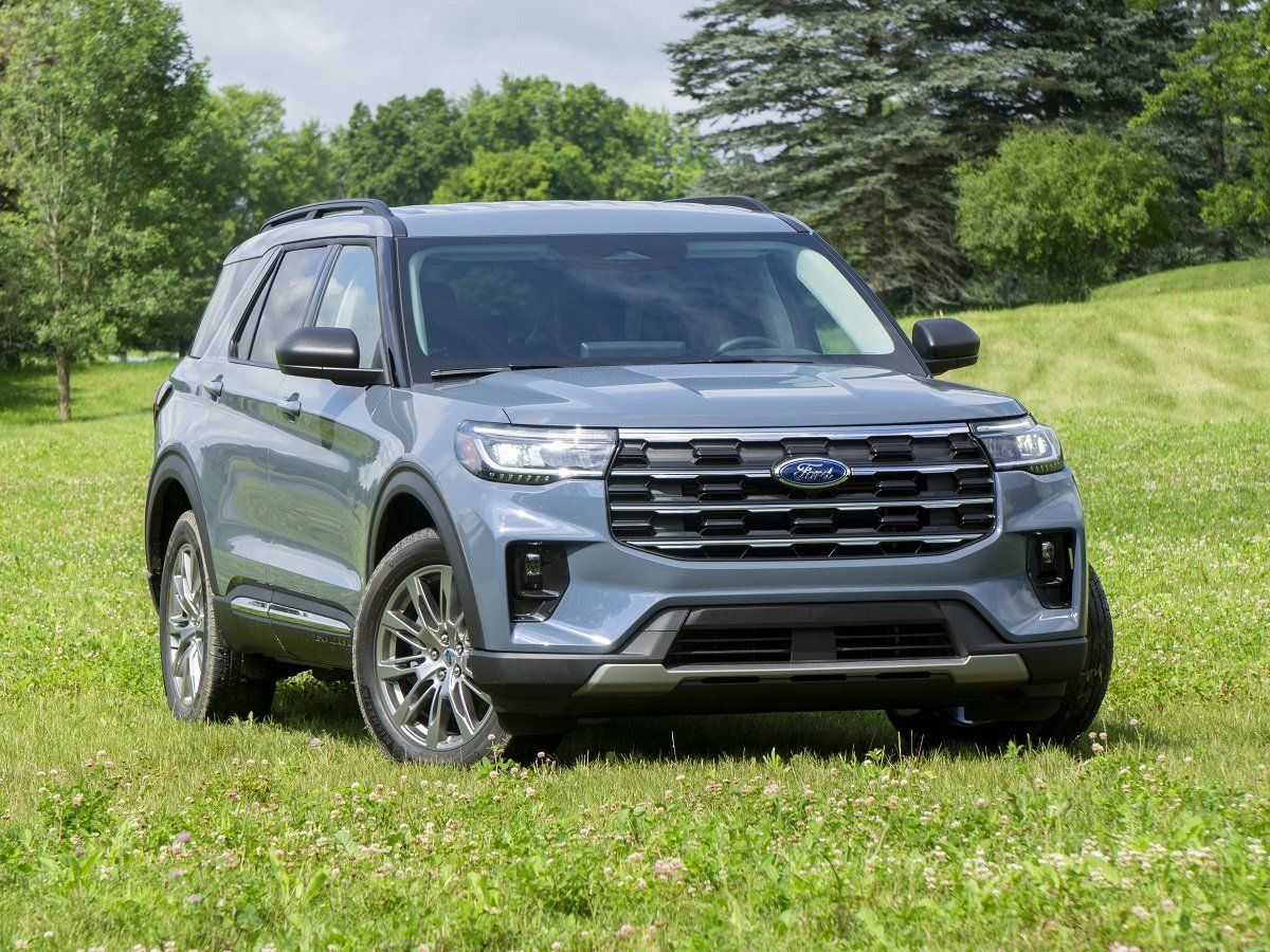 Gray SUV parked on a grassy field with trees in the background