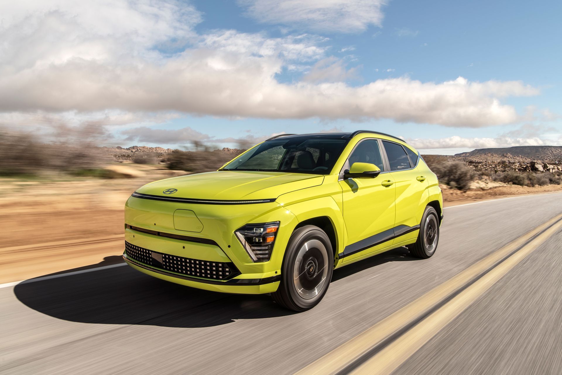 Bright lime green SUV driving on a desert highway under a cloudy sky