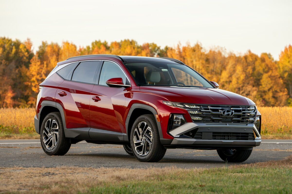 Red SUV parked on a road with autumn trees in the background