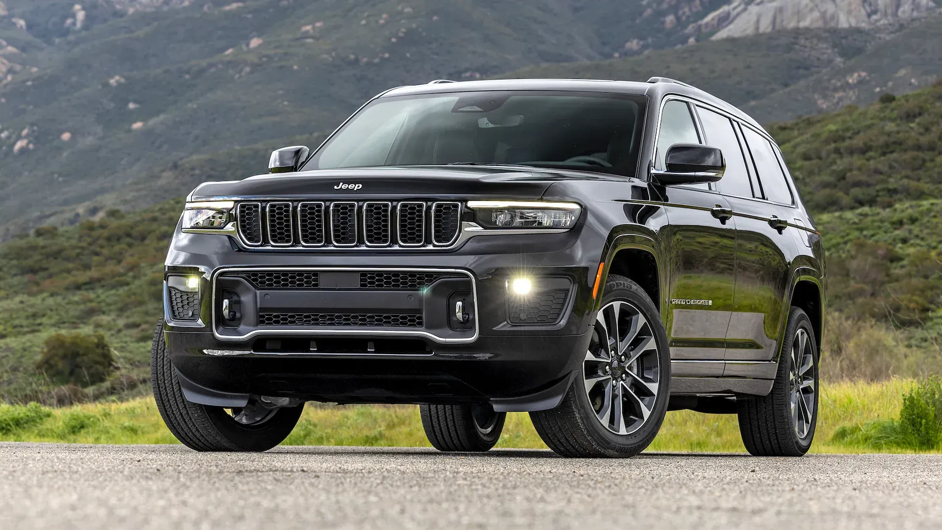 Black SUV driving on a mountain road with hills in the background