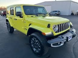 Bright yellow Jeep Wrangler parked outdoors on a paved lot, front three-quarter view