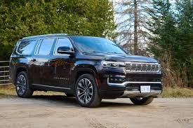 Black SUV parked on a dirt road with trees in the background