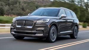 Dark gray SUV driving on a road with blurred trees in the background