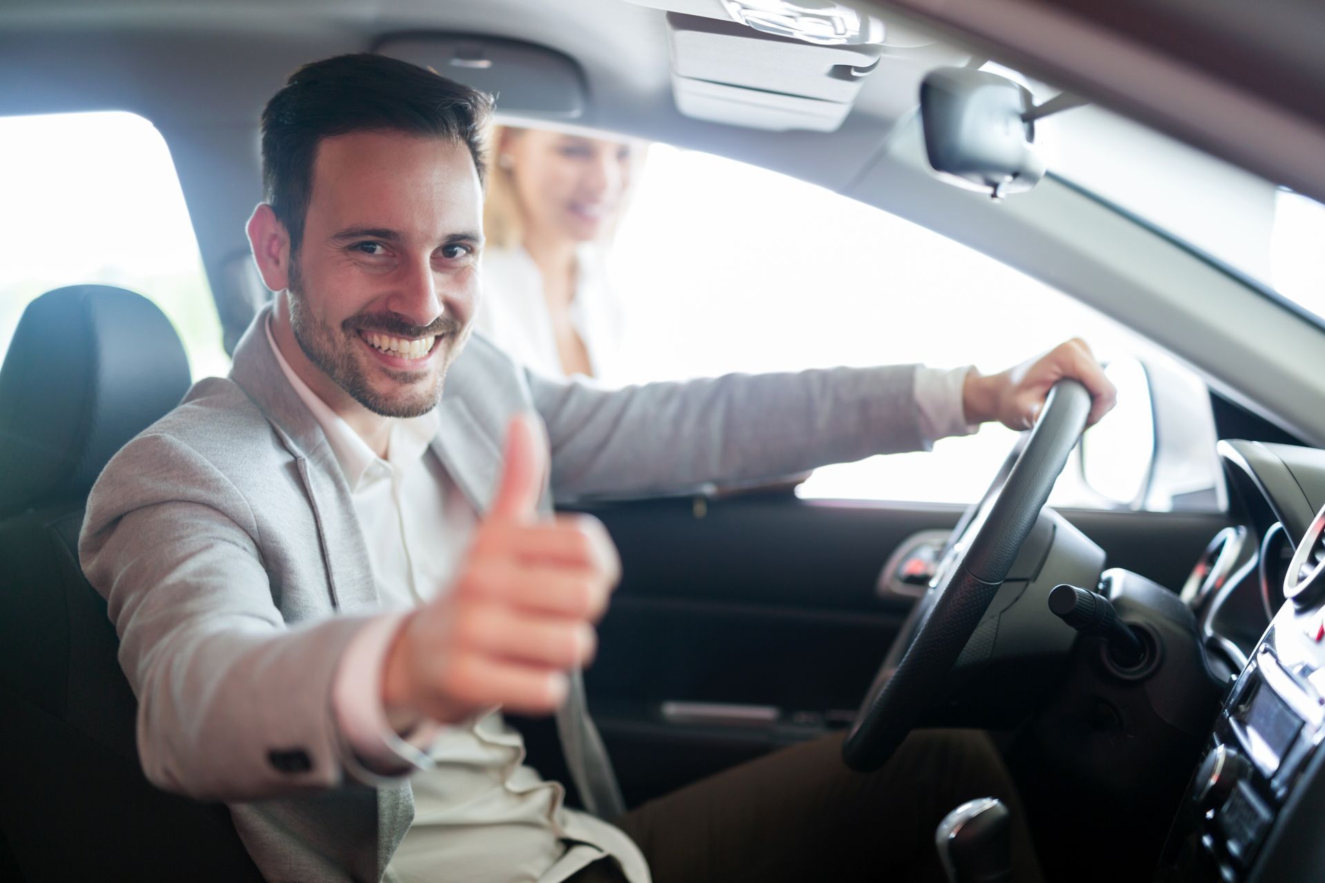 A man is giving a thumbs up while sitting in a car.