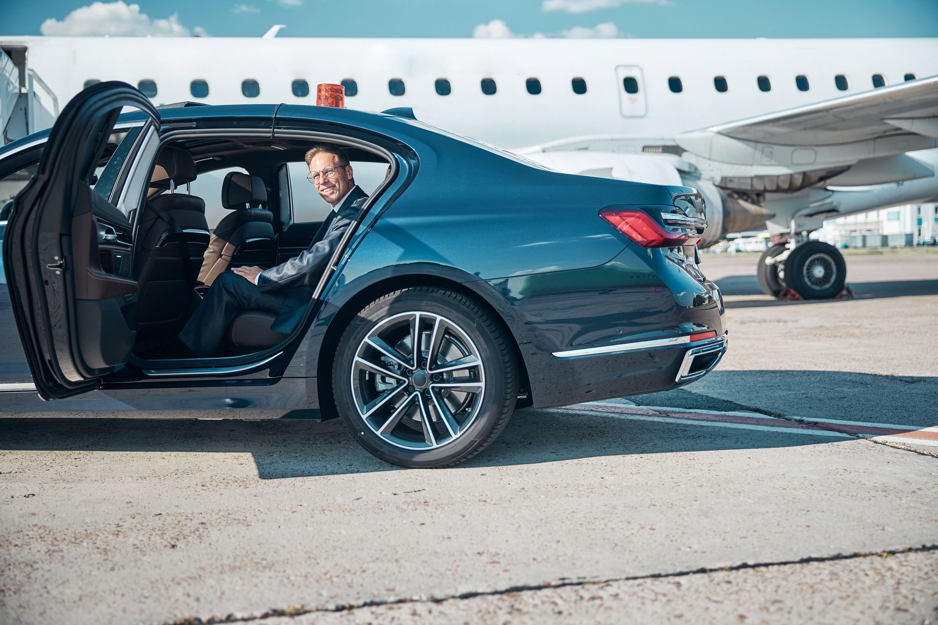 A man is getting out of a car next to an airplane.