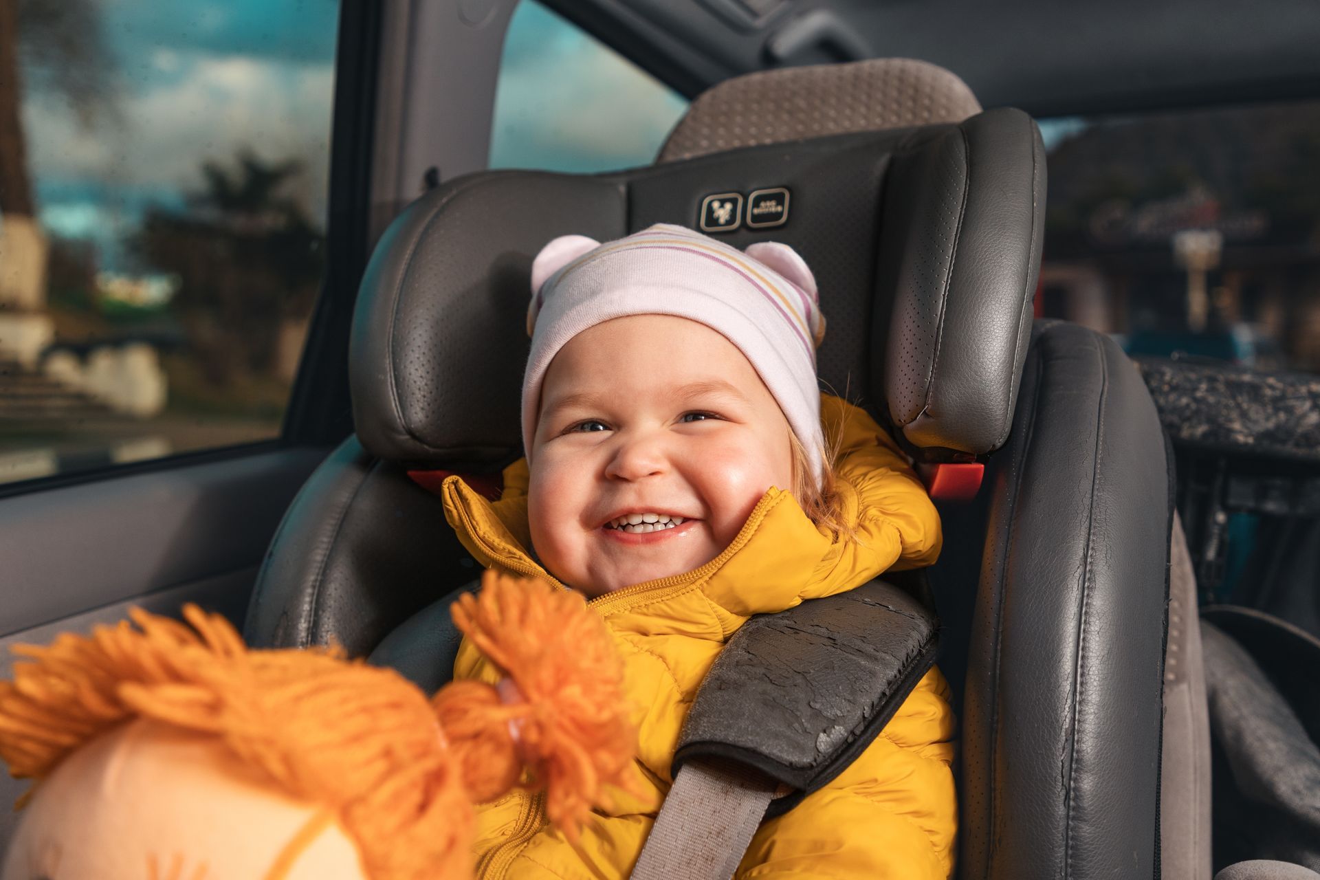 A baby is sitting in a car seat and smiling.