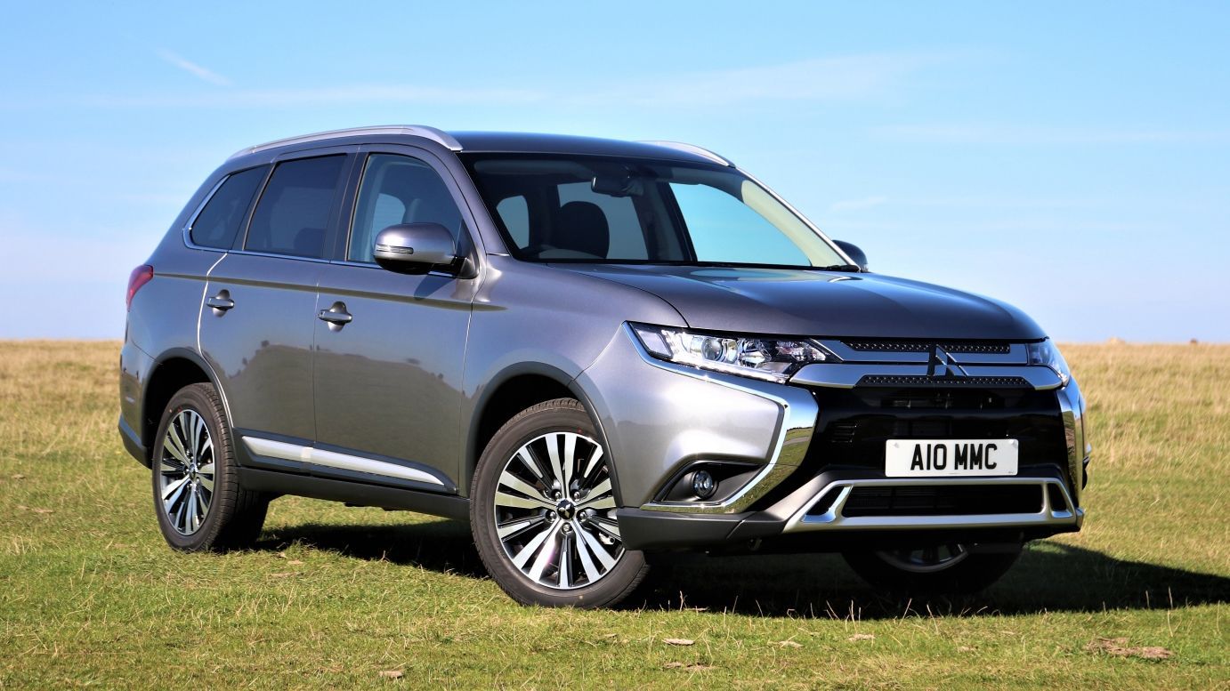 Grey SUV parked on grass in a sunny field under a blue sky